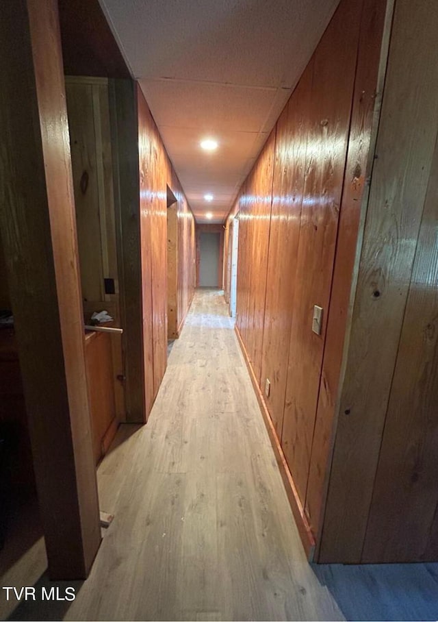 hall with light hardwood / wood-style flooring and wood walls