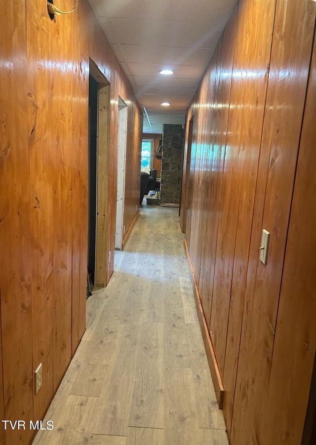 hallway featuring light hardwood / wood-style flooring and wooden walls