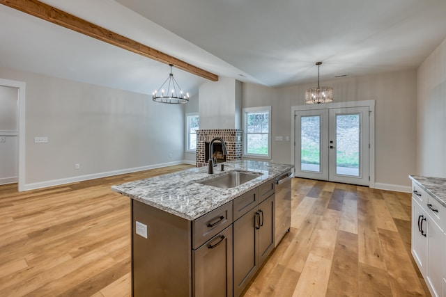 kitchen with light hardwood / wood-style floors, decorative light fixtures, a fireplace, an inviting chandelier, and sink