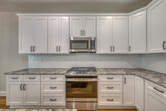 kitchen with white cabinets, appliances with stainless steel finishes, and tasteful backsplash