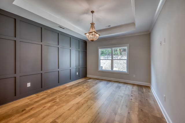 unfurnished bedroom with a tray ceiling, light hardwood / wood-style floors, and a chandelier