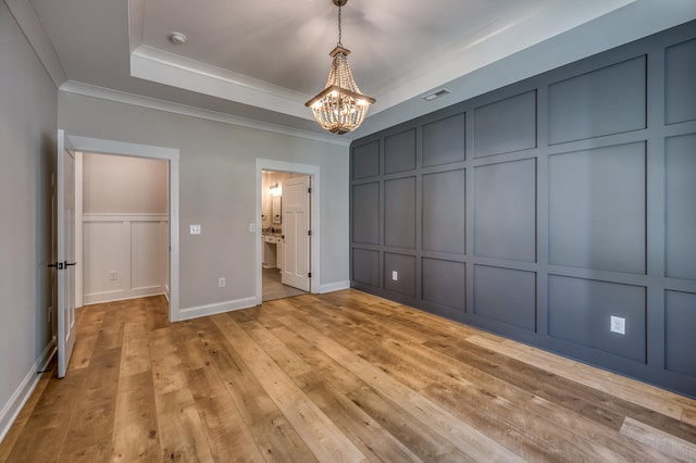 unfurnished bedroom with light hardwood / wood-style flooring, a notable chandelier, and a tray ceiling