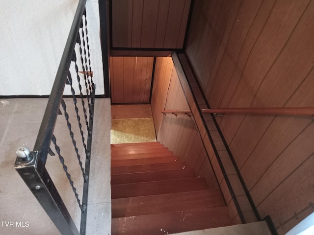 stairway featuring wood walls