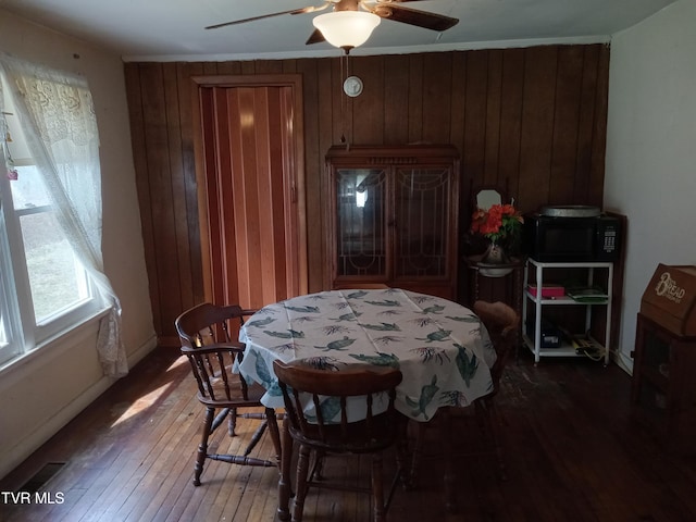 dining area with wooden walls, ceiling fan, and dark hardwood / wood-style floors