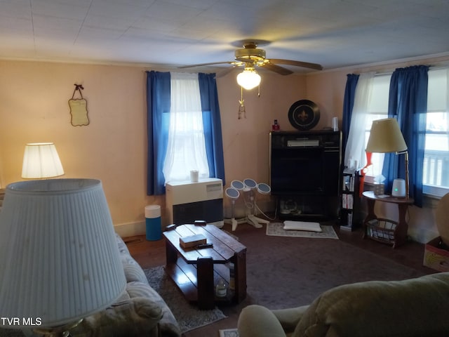 living room featuring ceiling fan, ornamental molding, dark wood-type flooring, and a healthy amount of sunlight