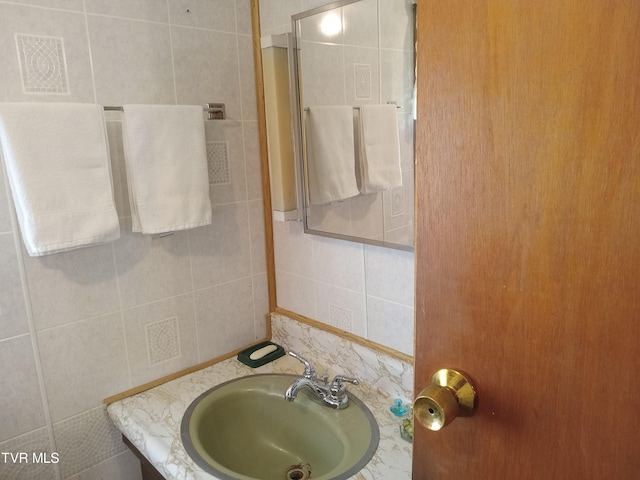 bathroom featuring sink and tile walls