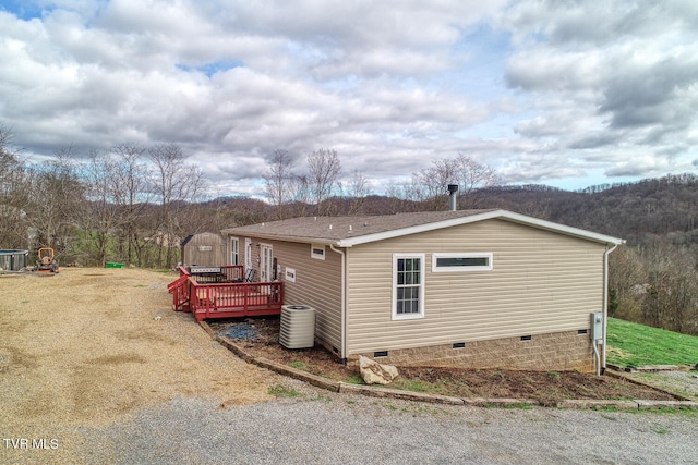 view of home's exterior featuring a wooden deck, central AC, and a yard