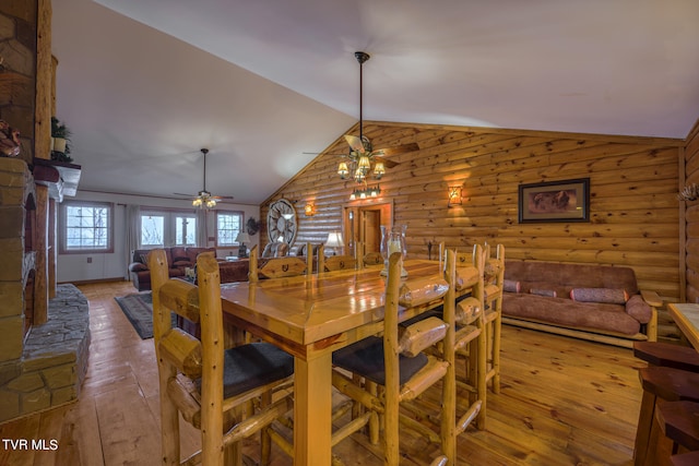 dining area with ceiling fan with notable chandelier, lofted ceiling, hardwood / wood-style floors, and rustic walls