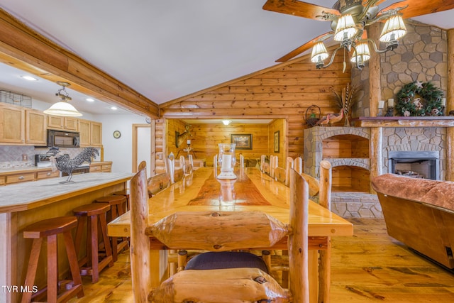 dining room featuring lofted ceiling with beams, a fireplace, light wood-type flooring, and ceiling fan