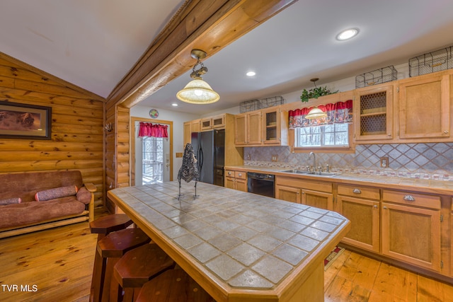 kitchen featuring log walls, black appliances, decorative backsplash, vaulted ceiling, and tile countertops