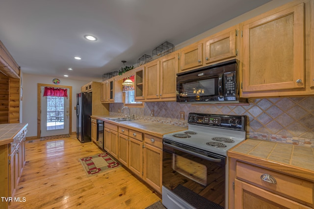 kitchen with tile counters, black appliances, a wealth of natural light, and tasteful backsplash