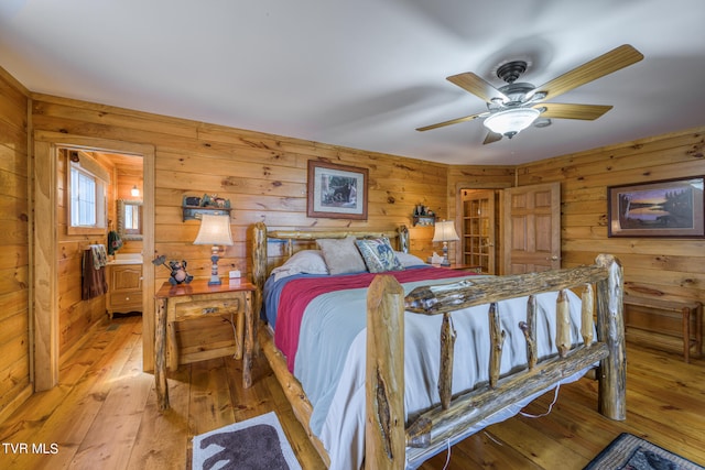 bedroom featuring ceiling fan, wooden walls, and light hardwood / wood-style floors