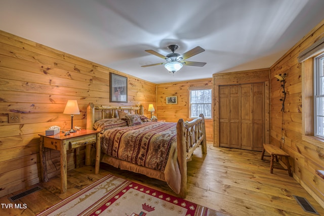 bedroom featuring ceiling fan, wooden walls, and light hardwood / wood-style flooring