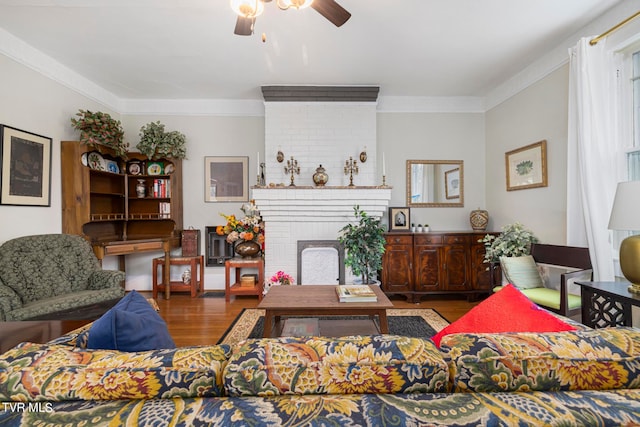 living room featuring crown molding, ceiling fan, dark hardwood / wood-style flooring, and a fireplace