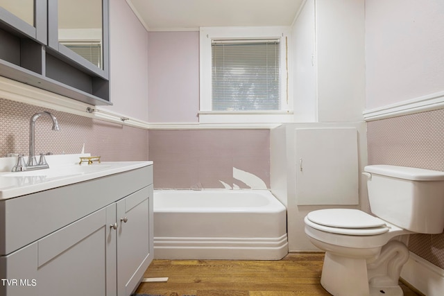 bathroom with a tub, vanity with extensive cabinet space, toilet, and wood-type flooring