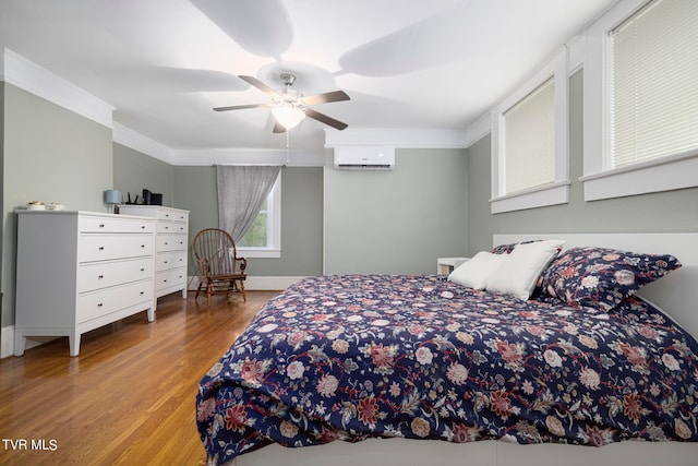 bedroom featuring a wall mounted air conditioner, ornamental molding, ceiling fan, and light hardwood / wood-style flooring