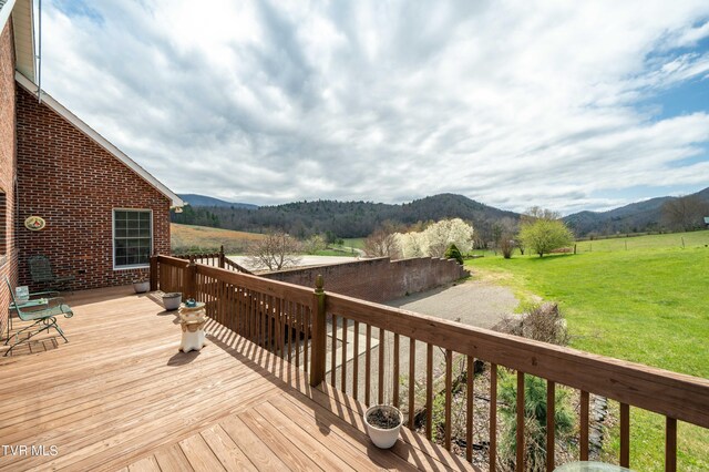 wooden terrace with a mountain view, a rural view, and a lawn