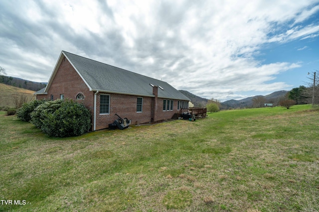 exterior space with a deck with mountain view and a yard