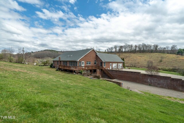 rear view of property featuring a deck, a rural view, and a yard