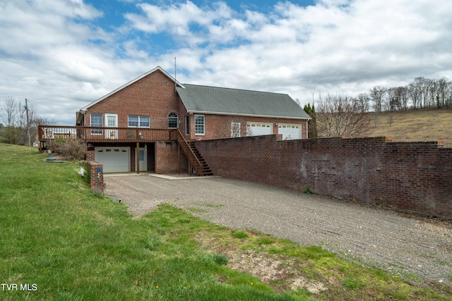 view of front of home with a wooden deck, a front lawn, and a garage