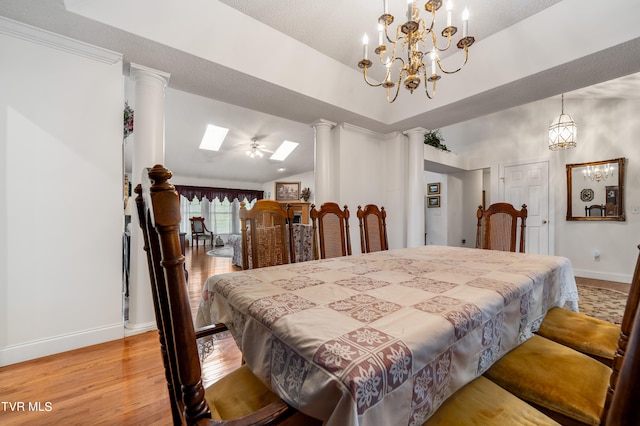 dining space with an inviting chandelier, lofted ceiling, light hardwood / wood-style floors, and ornate columns