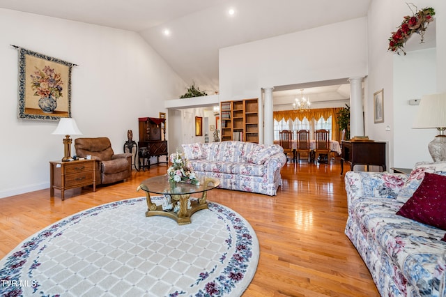 living room featuring light wood-type flooring, high vaulted ceiling, a chandelier, and ornate columns