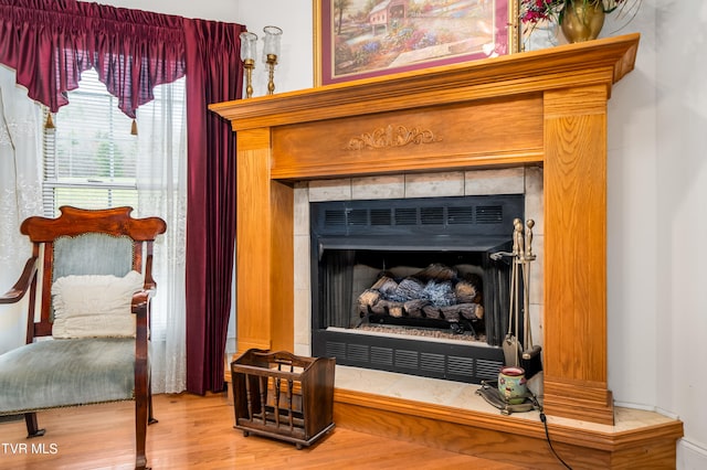 interior details featuring a tiled fireplace and light wood-type flooring