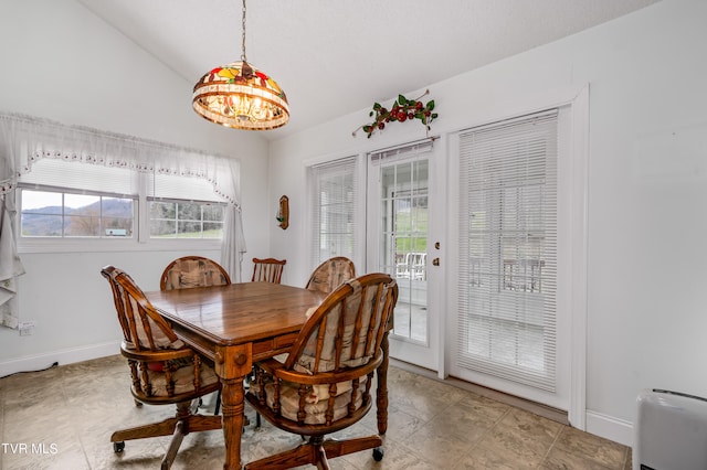 dining space featuring lofted ceiling, light tile floors, and an inviting chandelier