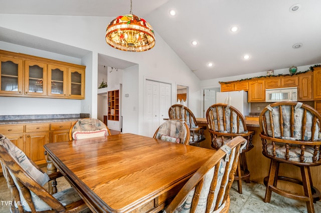 dining room with an inviting chandelier, high vaulted ceiling, and light tile floors