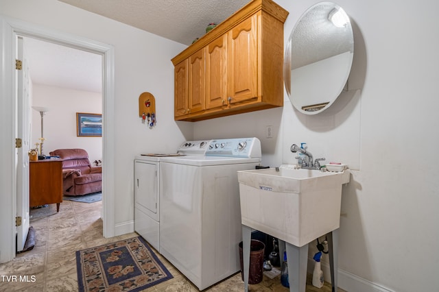 laundry room featuring a textured ceiling, cabinets, separate washer and dryer, and light tile floors