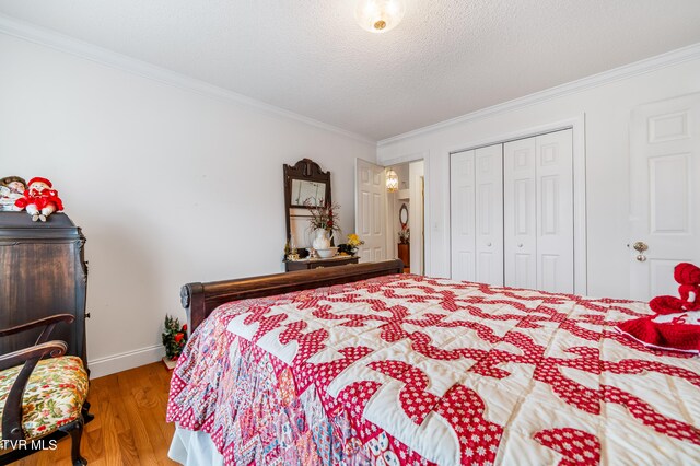 bedroom with a closet, hardwood / wood-style floors, a textured ceiling, and ornamental molding