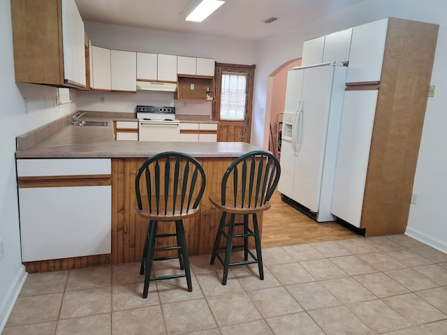 kitchen featuring a breakfast bar, white cabinetry, sink, and white appliances