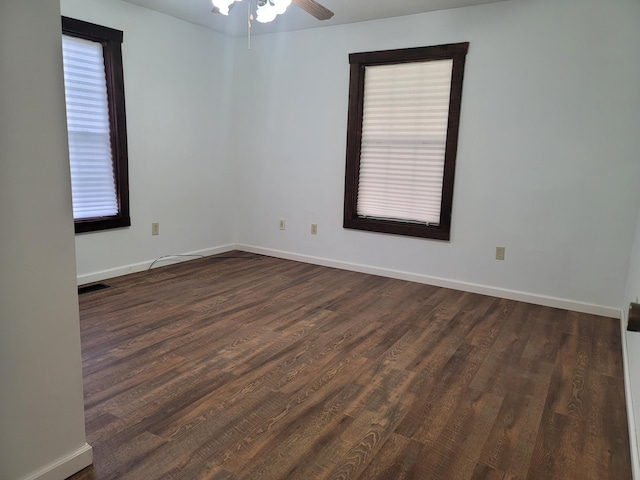 empty room featuring ceiling fan, a wealth of natural light, and dark hardwood / wood-style flooring