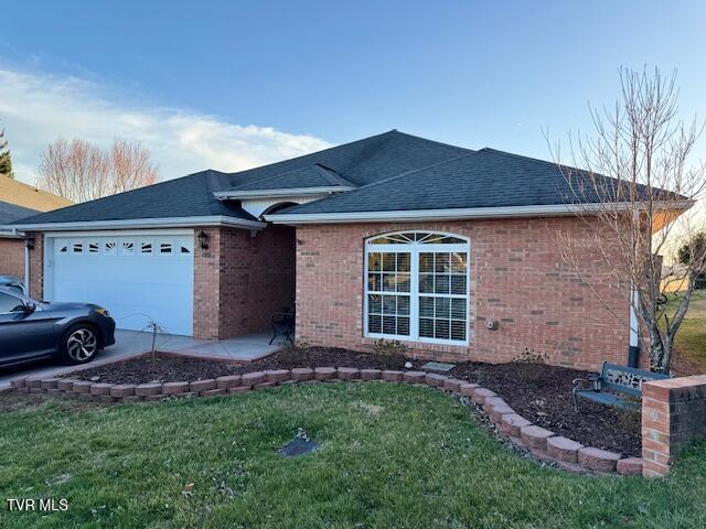 view of home's exterior with brick siding, a lawn, an attached garage, and roof with shingles