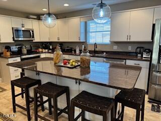 kitchen with a breakfast bar, dark countertops, appliances with stainless steel finishes, and a sink