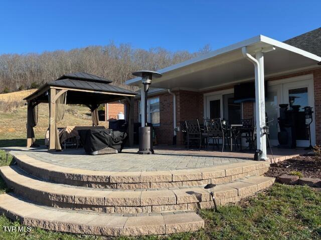 back of property with a gazebo, brick siding, and a patio