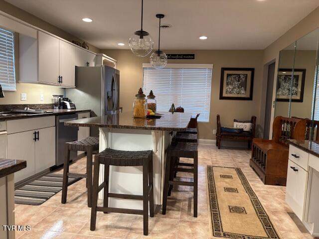 kitchen featuring a kitchen breakfast bar, a kitchen island, recessed lighting, appliances with stainless steel finishes, and baseboards