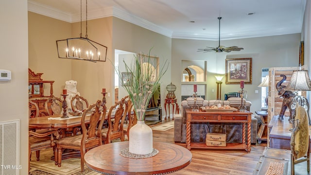 dining area featuring ceiling fan with notable chandelier, visible vents, crown molding, and light wood-type flooring