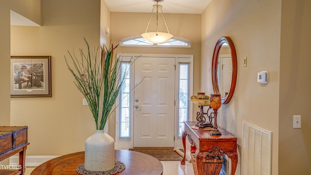 entryway with baseboards, visible vents, and a towering ceiling