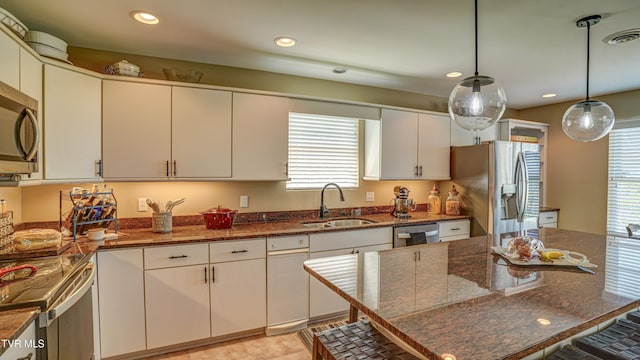 kitchen featuring a sink, pendant lighting, dark stone countertops, stainless steel appliances, and visible vents