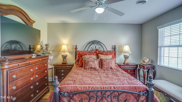 bedroom featuring baseboards, visible vents, a ceiling fan, and wood finished floors