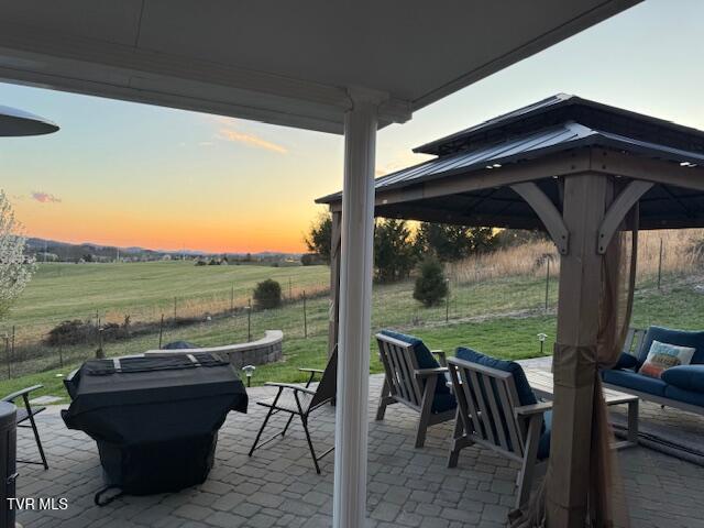 view of patio featuring a rural view, fence, and a gazebo