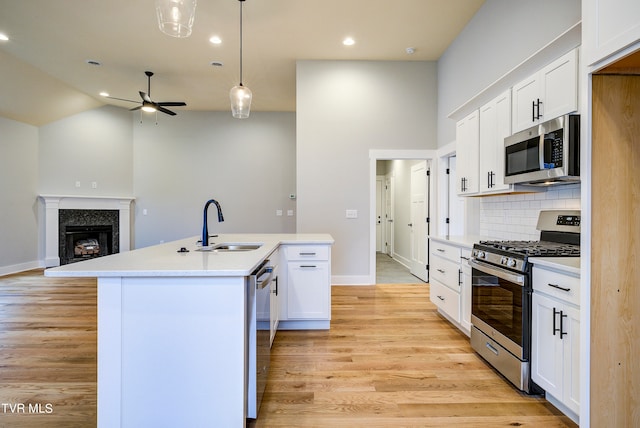 kitchen with light hardwood / wood-style flooring, backsplash, appliances with stainless steel finishes, and ceiling fan