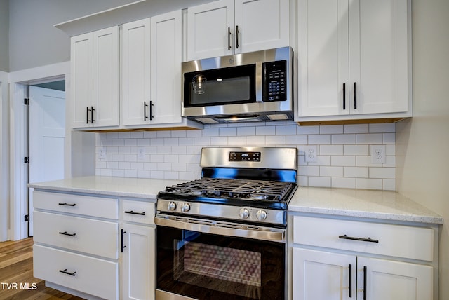 kitchen featuring white cabinets, appliances with stainless steel finishes, tasteful backsplash, and light stone countertops