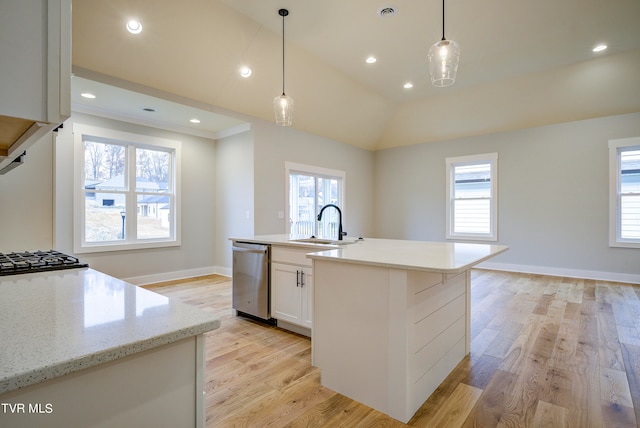 kitchen with light wood-type flooring, appliances with stainless steel finishes, a wealth of natural light, and a center island with sink