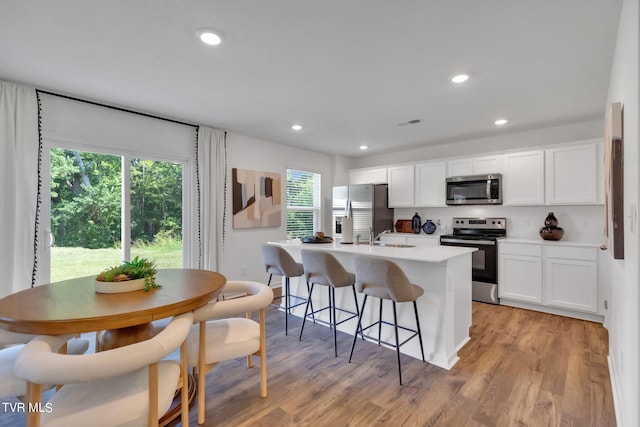 kitchen with appliances with stainless steel finishes, a wealth of natural light, and white cabinets