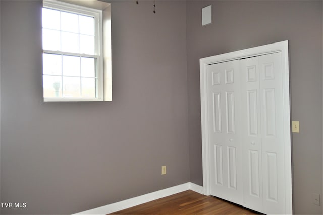 unfurnished bedroom with multiple windows, dark hardwood / wood-style floors, and a closet