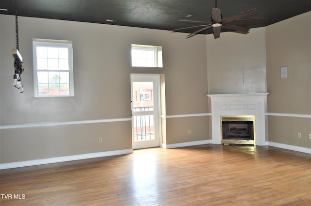 unfurnished living room with ceiling fan, a healthy amount of sunlight, and light hardwood / wood-style floors