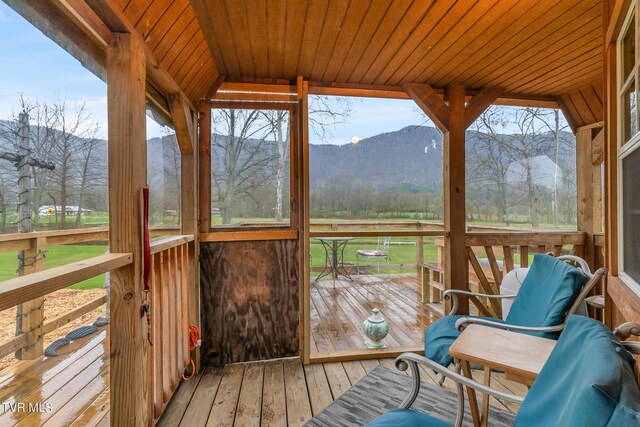 sunroom / solarium featuring wooden ceiling and a mountain view