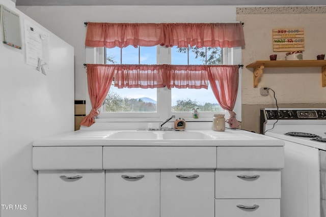 kitchen with electric range, sink, a healthy amount of sunlight, and white cabinetry